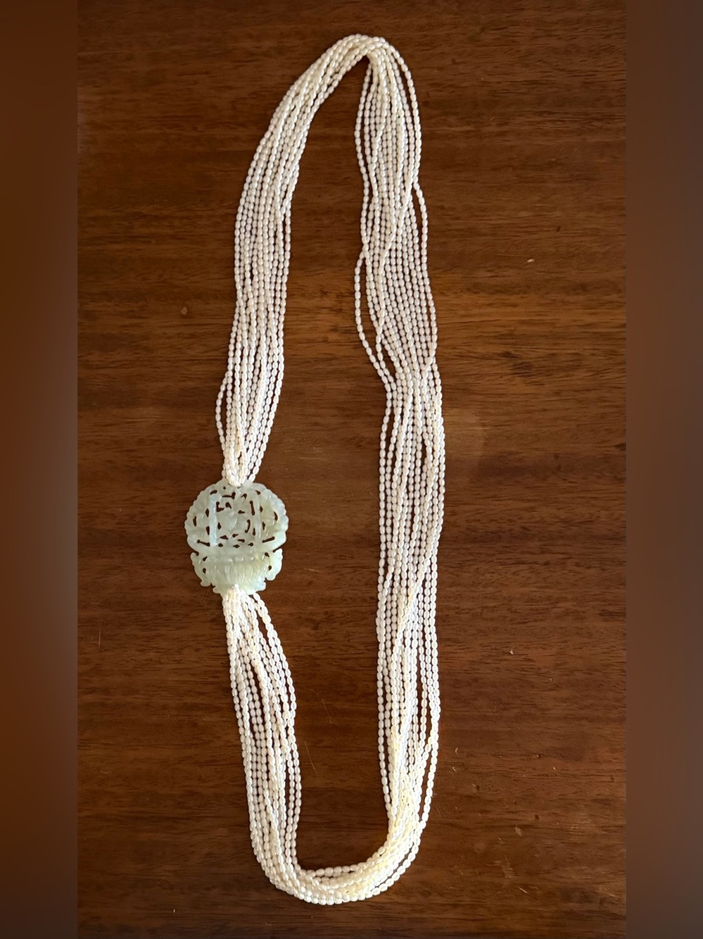 Hand carved apple jade pendant with freshwater pearl seed beads. 13 strands 38”
